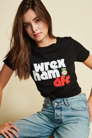 Photo of female model wearing black tee with wrexham afc written out in lower case block letters along with an image of the wrexham crest. White and Red text, Short Sleeve 