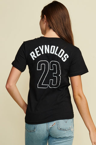 Cropped photograph the back of a female model wearing a black short sleeve tee with Reynolds written across the top and the number 23 below, white text