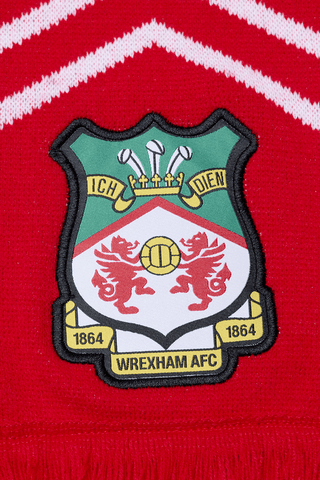 close up photo of the scarf showing the detail of the club badge which is sewn onto the bottom of the scarf near the tassles