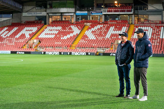 Photo of Rob Mcelhenney and Ryan Reynolds standing on Racecourse pitch. 