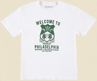 flat lay photo of a white youth short sleeve tee with the words "welcome to philadelphia" in green across the front