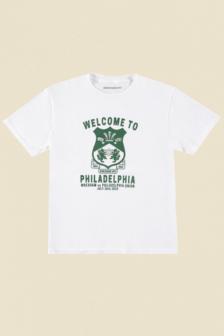 flat lay photo of a white youth short sleeve tee with the words "welcome to philadelphia" in green across the front